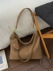 Large tan leather tote bag with gold chain strap and mini pouch charm on shoulder bag