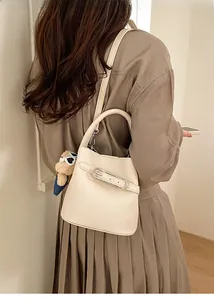 Chic cream bucket bag with litchi grain leather and cute plush bear charm detail