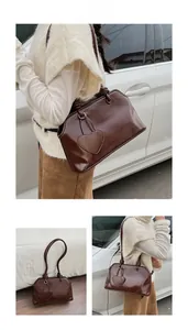 Macro detail of dark brown leather tote bag featuring heart pocket and pleated handle design