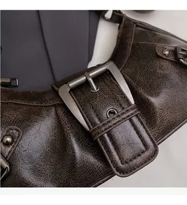 Detail of vintage moto style bag featuring distressed leather and silver metal buckles