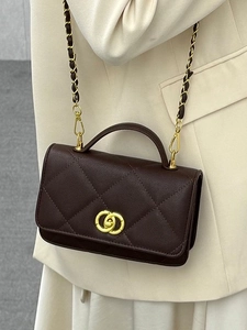 Elegant dark brown quilted crossbody bag with gold hardware and chain strap on suit