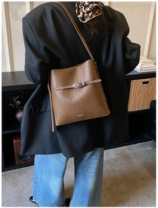 Sac seau en cuir grainé marron foncé porté avec un blazer et un jean en denim bleu