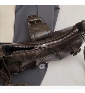 Close-up of smooth silver metal zipper and cracked leather texture on a retro brown bag