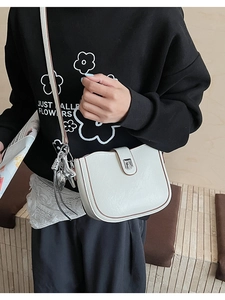 Detailed close-up of white leather saddle bag with silver buckle and heart charm