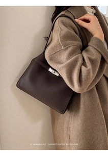 Détail d'un sac cabas en cuir grainé marron foncé avec un fermoir pivotant en métal argenté