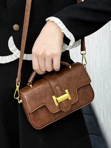Vintage dark brown crossbody bag with gold H-buckle shown held against black tweed jacket