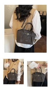 Detail of dark grey textured leather handbag with gold logo and white contrast stitching