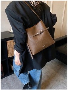 Gros plan détaillé du sac seau en cuir marron foncé avec motif de grain de litchi