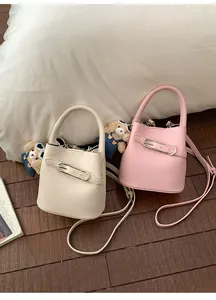 Detail of lychee pattern leather bucket bag with metal clasp and teddy bear charm
