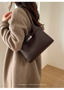 Vue détaillée du sac seau en cuir grainé marron foncé avec fermoir rotatif argenté