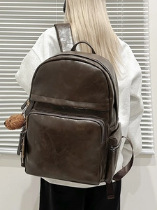 Vintage dark brown PU leather backpack for students with a plush bear charm on white background