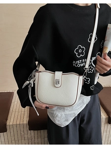 Detail of white textured leather bucket bag with silver clasp and metal star charm