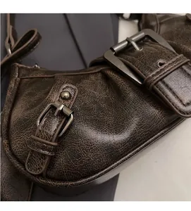 Detail of vintage textured dark brown faux leather shoulder bag with dark metal buckles