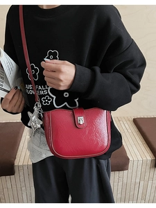 Close-up of bright red saddle bag featuring a silver star pendant and metallic buckle