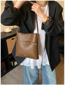 Détail du sac seau marron foncé en cuir grainé avec logo NORA & BESS doré élégant