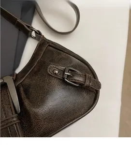 Detail of dark brown baguette bag featuring vintage cracked leather and gunmetal hardware