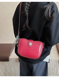 Detail of red leather bucket bag with silver metal buckle and grey tassel on a model