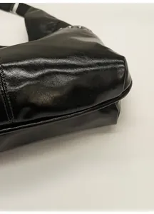 Vue détaillée des coutures de bordure et rivets d'un sac en cuir noir brillant chic