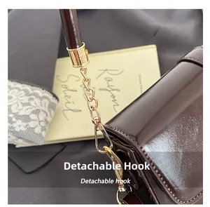 Detail of the golden detachable hook and chain on a glossy brown underarm bag