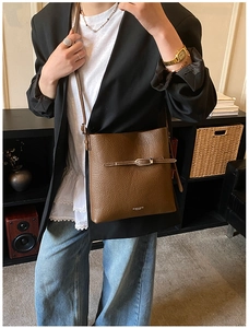 Détail du sac seau en cuir marron foncé avec boucle métallique et bandoulière réglable