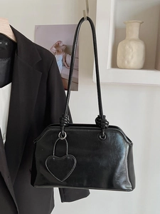 Classic black leather tote with knotted strap and heart charm in a retro minimalist style