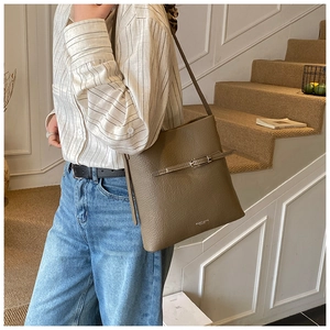 Détail macro du sac cabas en cuir grainé taupe avec boucle argentée et bandoulière chic