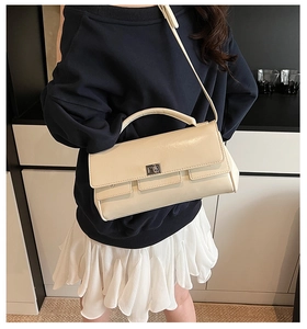 Detail of cream rectangular flap handbag with silver twist lock and adjustable strap