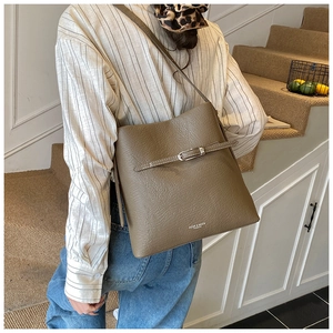 Détail du sac seau kaki foncé montrant le cuir grainé et la sangle à boucle argentée