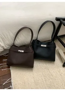Détail de sacs en cuir grainé marron foncé et noir avec fermoir rotatif en métal argenté