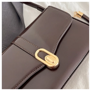 Detailed close-up of dark brown glossy leather texture and golden oval metal buckle