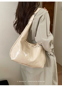 Détail du sac hobo crème avec œillets argentés et une finition polie brillante