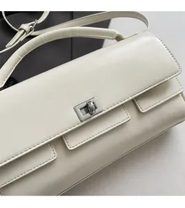 Close-up of cream rectangular handbag showing smooth leather and silver square turn-lock