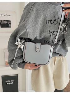Detail of light blue crossbody bucket bag with silver charms and snap closure