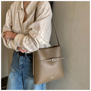 Détail du sac seau marron en cuir litchi avec fine bandoulière et boucle décorative