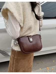 Close-up of brown vintage leather saddle bag with silver buckle in an outdoor setting