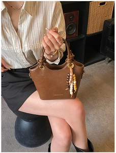 Detail view of brown bucket bag with knot handle and vintage colorful bead tassel