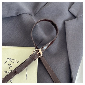 Detail of brown leather strap with adjustable gold buckle and precise stitching