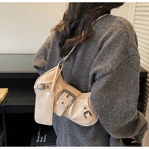 Detailed close-up of cream crescent shoulder bag with metallic buckles and small pouch