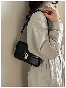 Detail showing high-shine black leather texture and gold oval buckle on the shoulder bag