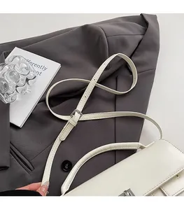 Close-up of white leather handbag with silver clasp and adjustable shoulder strap