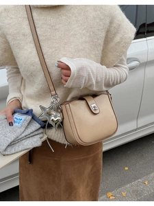 Close-up of beige crossbody bag with silver heart charms on a model in sunlight