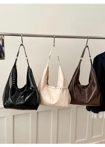 Trois sacs hobo en noir, beige et marron foncé avec détails d'oeillets en métal