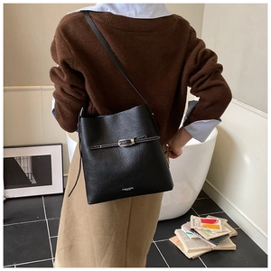 Détail d'un sac seau en cuir noir grainé avec boucle décorative et fine bandoulière