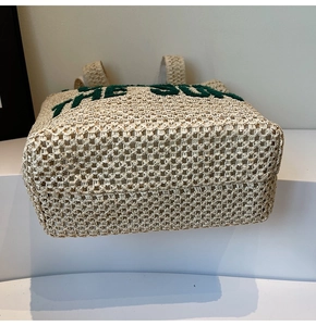 Close-up of woven straw tote bag base and texture featuring THE SUN lettering detail