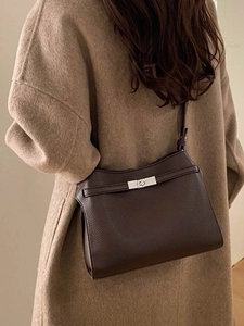 Sac bandoulière en cuir marron foncé porté sur un manteau beige, vue de dos