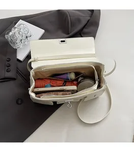 Spacious interior of beige leather flap bag showing storage for phone and umbrella