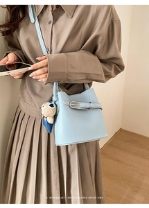Close-up of light blue lychee pattern leather bucket bag with a cute bear charm detail