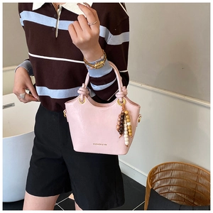 Detail of light pink bucket bag with wooden bead tassel and gold fashion logo