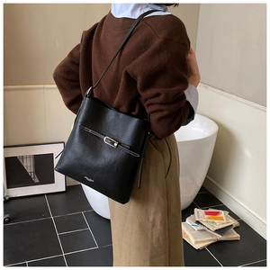 Détail du sac seau noir en cuir à grain de litchi avec surpiqûres blanches contrastantes