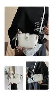 Detail of white lychee leather saddle bag with brown trim and star pendant